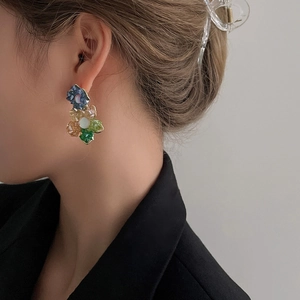 Détail des boucles d'oreilles fleur avec cristaux colorés portées par un mannequin