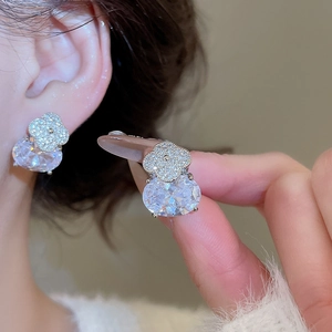 Vue détaillée des boucles d'oreilles trèfle en argent avec zircons tenue en main