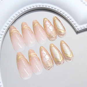 Elegant long almond press-on nails in nude pink with gold glitter and foil textures