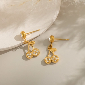 Chic gold-plated cherry earrings with sparkling crystals on minimalist stone display