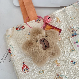 Macro detail of plush star bear charm with pink bell and embroidered facial features