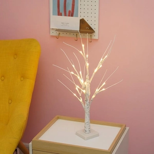 Warm white LED birch tree lamp with square base on wooden table in cozy indoor setting