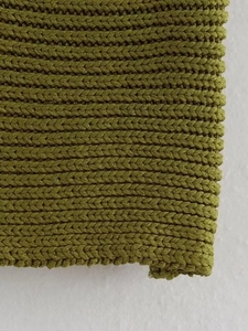 Detailed macro view of olive green chunky knit fabric with textured V-shaped patterns