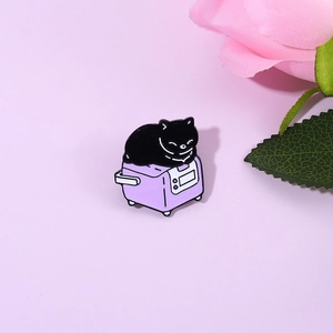 Close-up of a cute black cat enamel pin on a purple appliance with a floral background