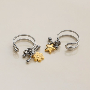 Detail of silver dual-band ring featuring gold star and flower charms on a glossy surface