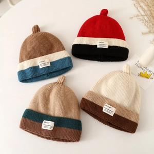 Set of four striped knitted baby beanies with pointed tops and woven tags for winter