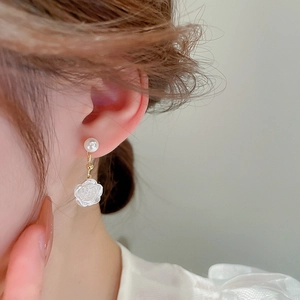 Detail of white flower and pearl earrings on model showing elegant french style