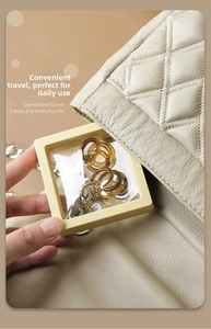 Macro view of portable square PE film jewelry box being placed into a quilted beige handbag