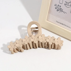 Close-up of beige matte flower hair claw clip on minimalist white surface background