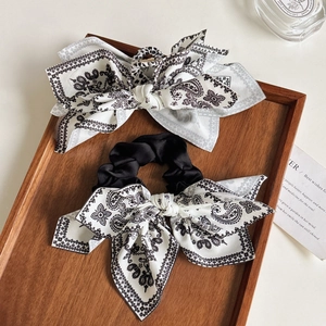 Detail of vintage paisley pattern hair bow clip and scrunchie on a dark wooden tray