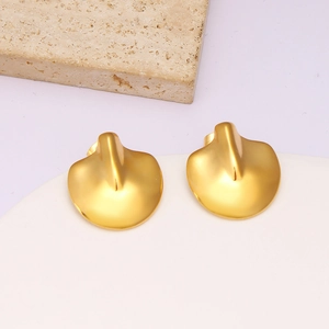 Macro shot of gold petal-shaped stud earrings with a brushed matte texture on stone