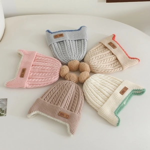 Detail of five knit baby hats in soft pastel colors with cute cat ears and pom-poms