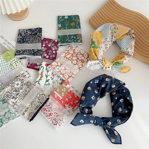 Various floral print square headscarves and hair ribbons in assorted colors on a white desk