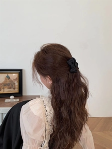Détail d'une pince à cheveux avec nœud en satin noir porté par un mannequin