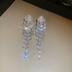Close-up of sparkling long tassel earrings with silver plating and zircon stones