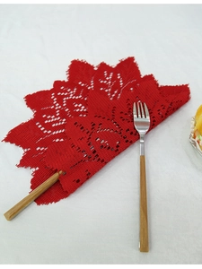 Detailed macro of red knitted lace placemat with floral cutout patterns and scalloped edges