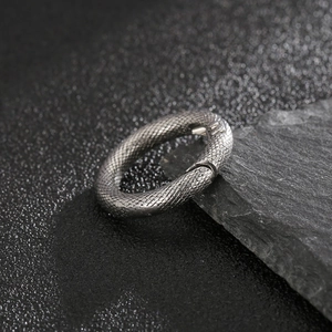 Macro shot of silver stainless steel spring ring with detailed snake scale pattern texture