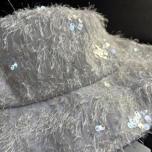 Détail macro des fibres de franges blanches et paillettes argentées sur ce chapeau bob
