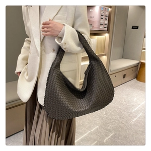 Close-up of the intricate dark brown leather woven texture and craftsmanship of the shoulder bag