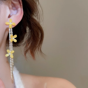 Detail of yellow flower drop earrings with pearl center and sparkling tassel fringe