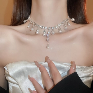 Close-up of pearl necklace with teardrop zircon pendant on a model's collarbone