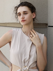 Detail of beige sleeveless dress featuring a stylish gold waist buckle and cut-out