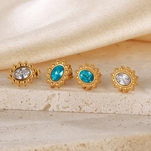 Detailed close-up of sunflower gold earrings with blue and clear crystals on silk
