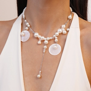 Detail of elegant pearl necklace with shell pendants and fringe tassels on a model