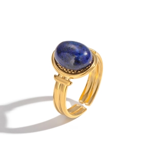 Détail d'une bague dorée ajustable avec une pierre ovale de lapis-lazuli bleu sur fond blanc