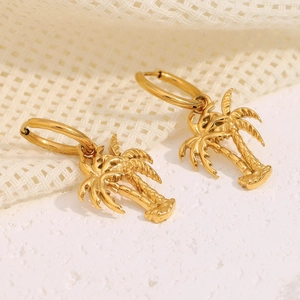 Macro detail of 18K gold plated stainless steel coconut tree pendant earrings on fabric