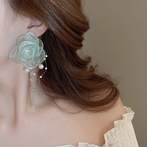 Detail of floral earring with mint green glitter petals, pearl accent, and tassel chain