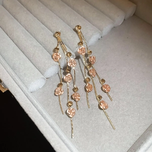 Détail de boucles d'oreilles rose avec glands et cristaux sur un plateau en velours