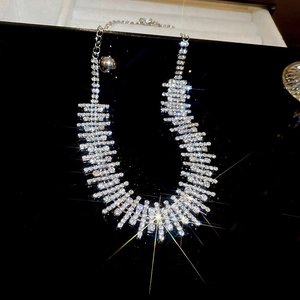 Detail of silver choker necklace with shimmering rhinestones on black reflective surface
