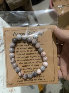 Close-up of pink zebra stone bead bracelet with a heart charm on a birthday gift card