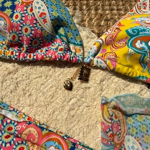 Detail of paisley print bikini with golden heart pendant and palm tree metal charm