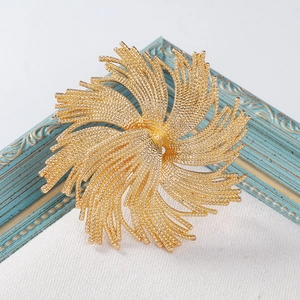 Detail of a gold vintage fireworks brooch with intricate mesh texture on blue frame background
