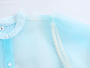 Dettaglio dello scollo e della spalla sulla camicia in organza blu con stampa di palme