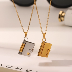 Close-up of book-shaped stainless steel pendants with heart cutout and 18K gold plating