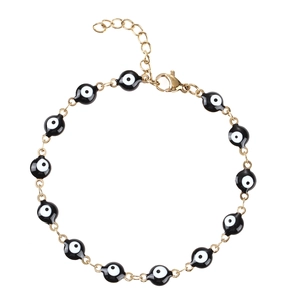 Dettaglio del bracciale a catena dorata con ciondoli occhio del diavolo bianchi e neri