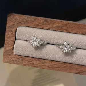 Minimalist silver star earrings with zircons displayed in a luxury wooden jewelry box