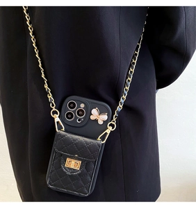 Detail view of black quilted phone case with butterfly ornament and gold chain strap