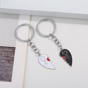 Detail of interlocking black and white enamel heart keychains with cute stick figures