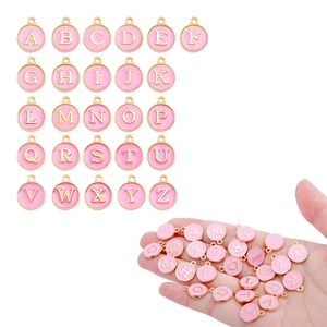 Detail of pink enamel A-Z round alphabet pendants with gold plating for DIY jewelry