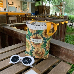 Detail of sunflower canvas mini bucket bag with yellow straps and stylish white sunglasses