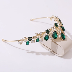 Detailed macro view of the golden leaf crown featuring emerald gemstones and clear rhinestones