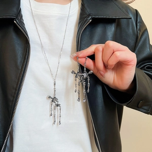 Detail shot of silver skull tassel necklace and earring set worn on a black leather jacket