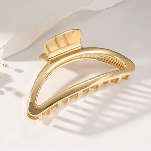 Macro detail of high-shine gold metal hair claw clip showing smooth mirror finish texture