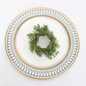 Close-up of mini PE pine needle wreath decoration on a geometric pattern ceramic plate