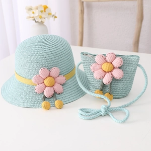 Detail of blue straw hat and matching bag with 3D pink flower and soft yellow pom-poms