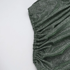 Detailed macro view of dark green glitter fabric with tight pleats and metallic threads